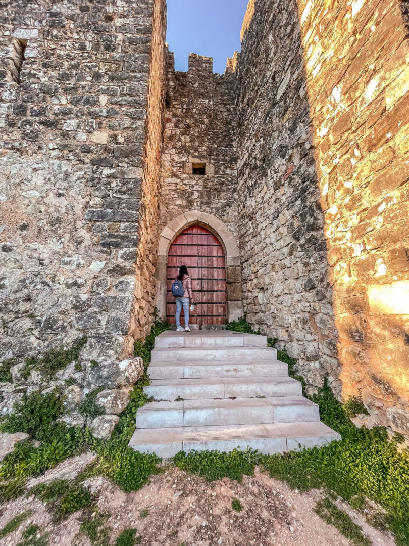 O castelo de Pombal com uma porta medieval fechada ao centro. Estou na frente da porta, de costas para a foto.