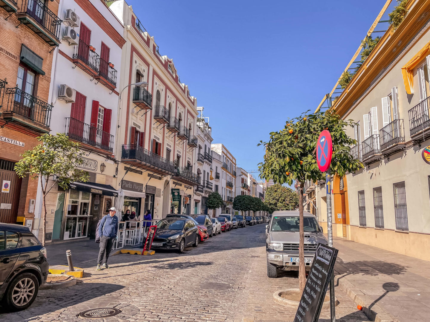 Foto de uns dos bairros de Sevilha, com construções de três andares coloridas, com pequenas sacadas de ferro em todas elas.