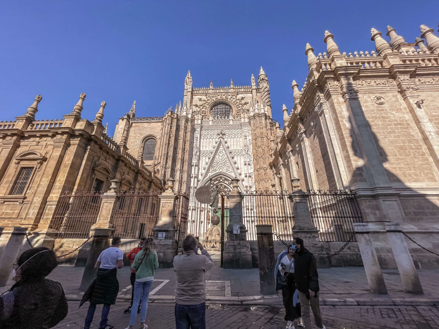 Foto de frente da catedral de Sevilha, com algumas pessoas na frente.