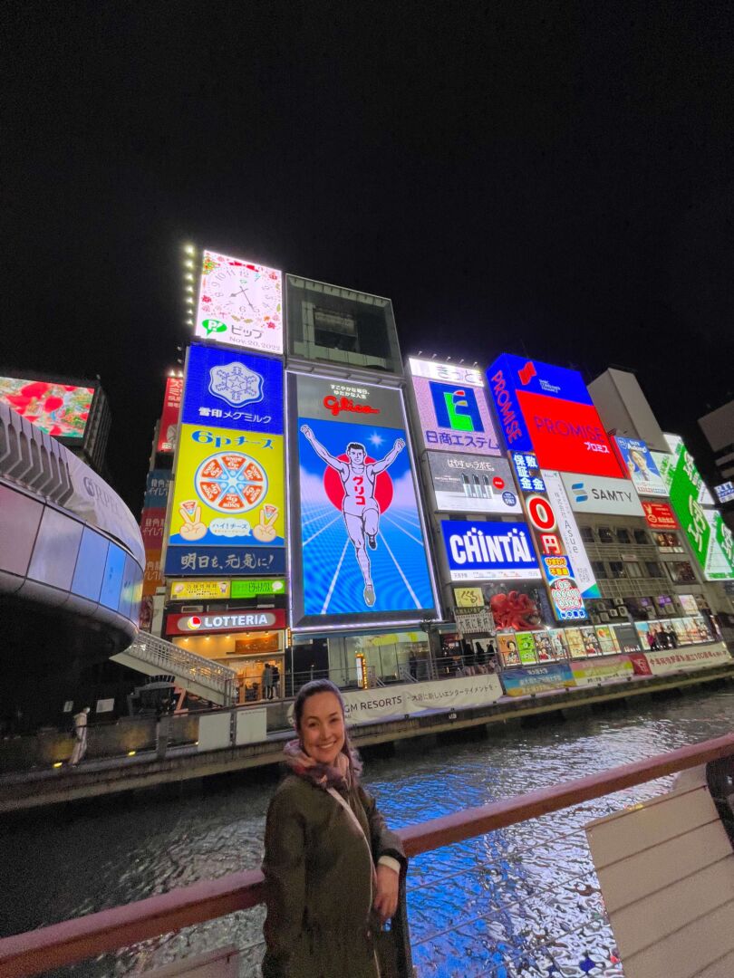 Eu em frente aos muitos letreiros luminosos em Osaka. 