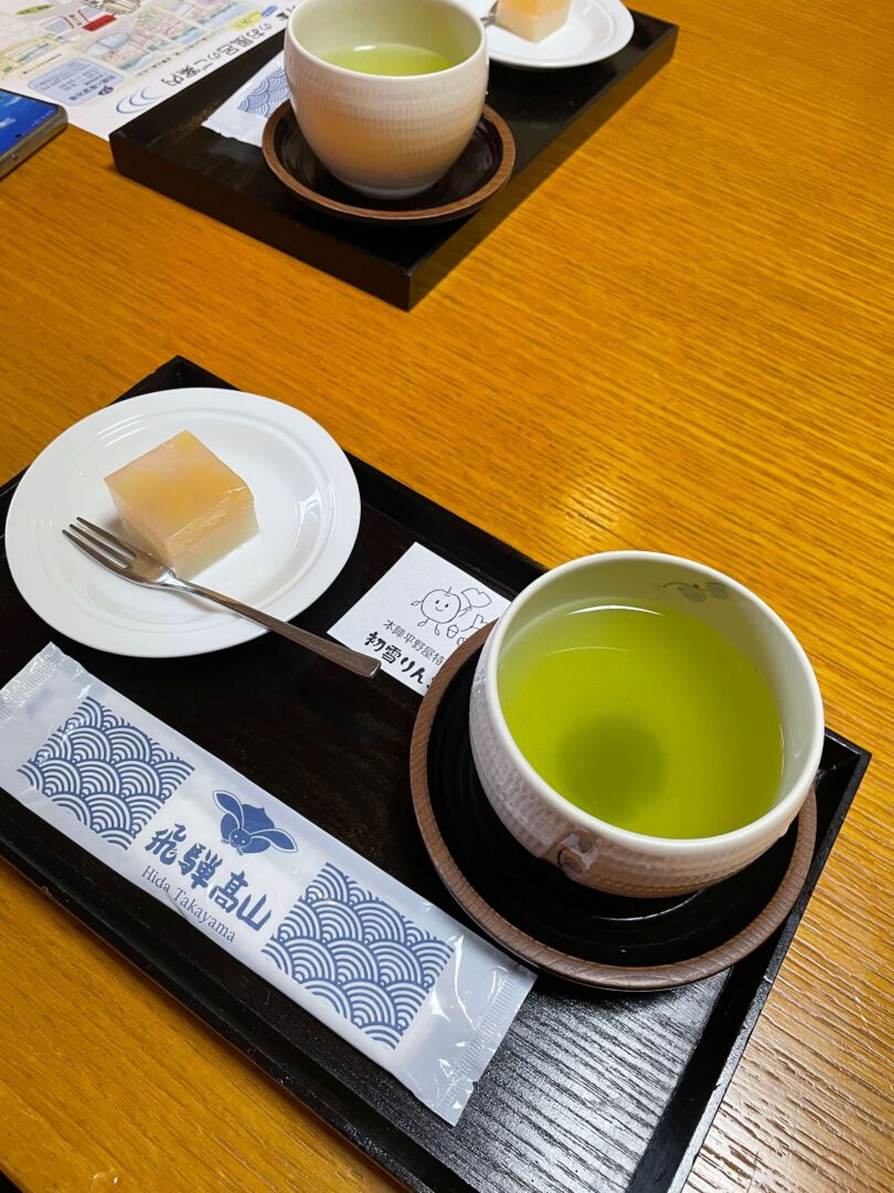 foto de cima, mostrando um chá verde em uma bandeja pequena, com um doce pequeno quadrado ao lado