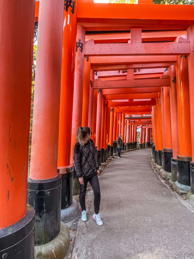 Um corredor de toriis vermelhos e eu embaixo olhando para trás.