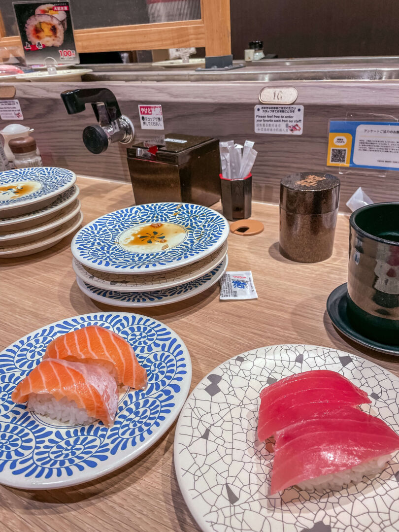 em um restaurante, com dois pratos de niguiri - comida japonesa - na frente. 