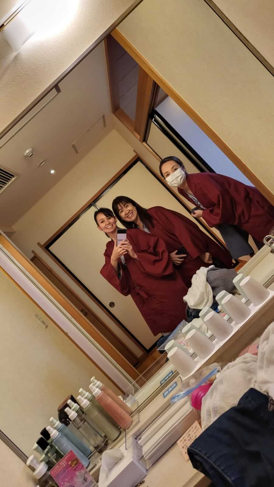 Eu, minha irmã e minha tia, de Kimono vermelho tirando uma foto em frente ao espelho.