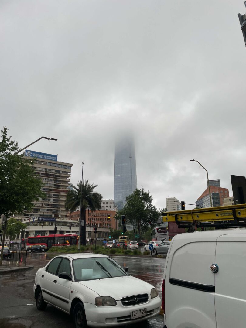 Imagem da rua de Santiago em um dia nublado, Ao fundo, o Sky costanera encoberto por nuvens.