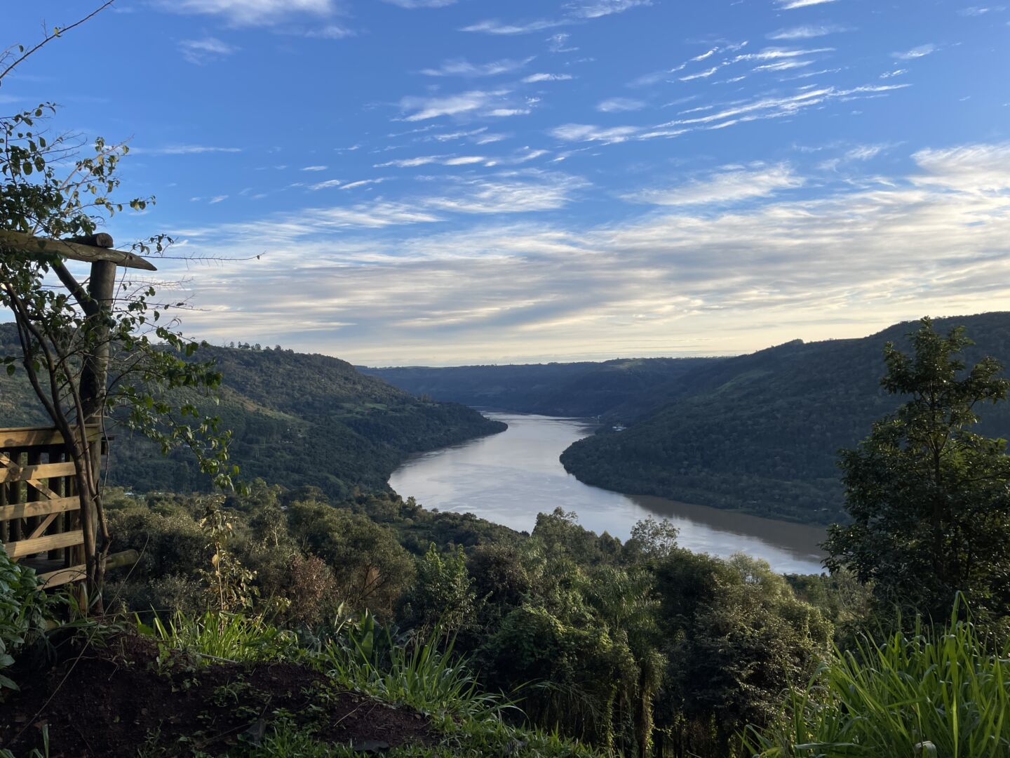 vista de um mirante, com um rio em curva no centro e um céu azul entre nuvens,